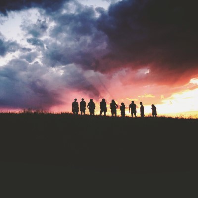 Group silhouetted by cloudy sunset