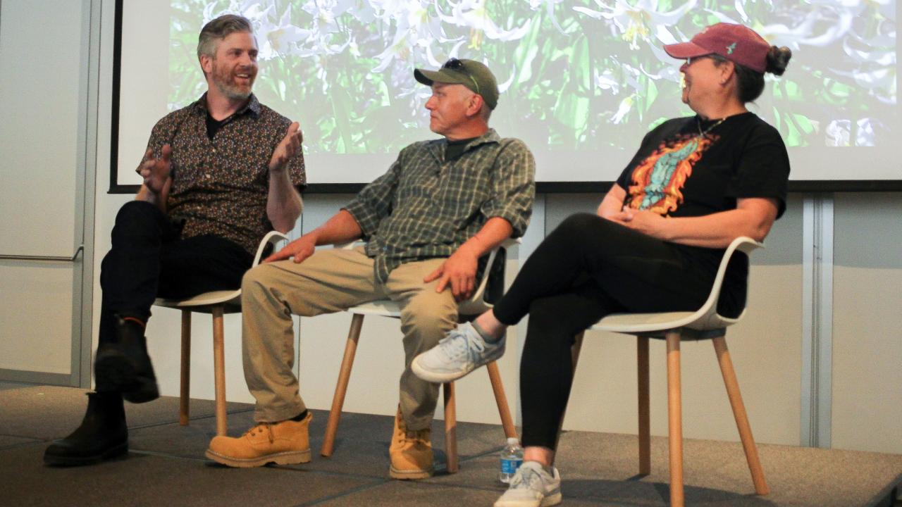 Three people hold a discussion on a small stage.