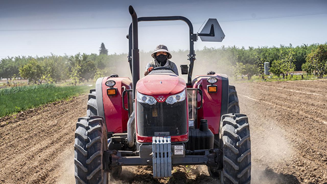 Front view of a red tractor being driven through a field