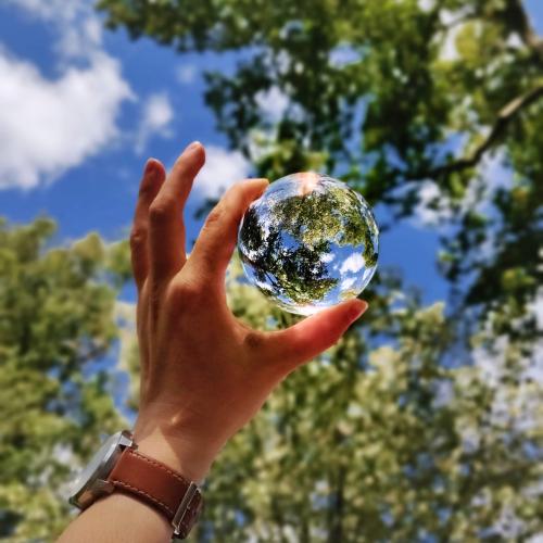 Hand holding up a glass sphere in the woods
